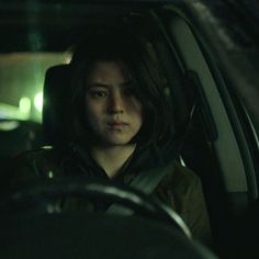 a woman sitting in the passenger seat of a car at night with her head turned to the side