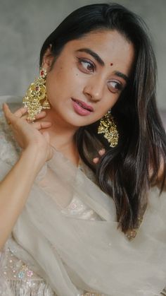 a woman in a white sari and gold earrings