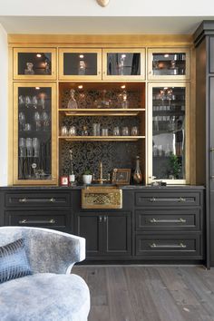 a kitchen with black cabinets and gold trimmings on the doors, glass fronted cupboards