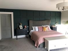 a bedroom with a bed, dresser and nightstands in front of a green paneled wall