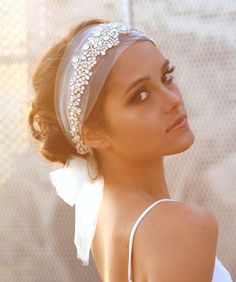 a woman wearing a headband with pearls and tulle on top of her head