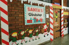 a group of people standing in front of a wall decorated with christmas decorations and santa's workshop signs