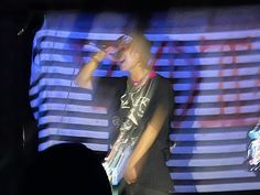 a man standing in front of a projection screen holding a cell phone to his ear