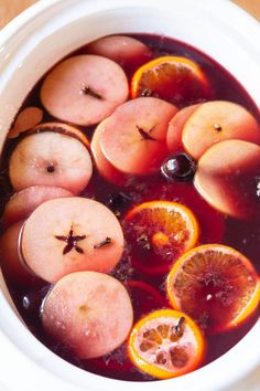 a white bowl filled with liquid and sliced fruit