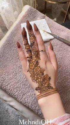 a woman's hand with henna on it and flowers painted on the palm