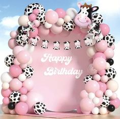 a pink and black cow birthday arch with balloons