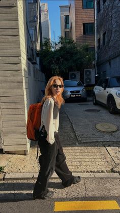 a woman is walking down the street with a backpack