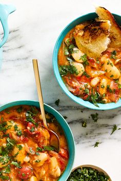 two bowls of soup with bread on the side