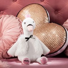 a white stuffed animal sitting on top of a pink couch next to pillows and hearts