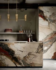 a kitchen with marble counter tops and cabinets in the center, along with gold pendant lights