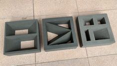 three cement blocks sitting on top of a floor next to each other with holes in them