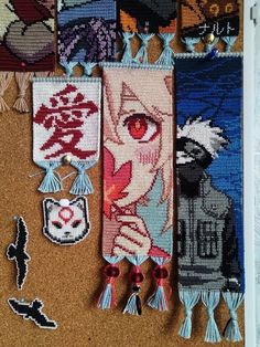 several pieces of cross - stitched art hanging on a wall with tassels