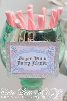 pink and silver candy sticks in a green glass container with a sign on it that says sugar plum fairy wands