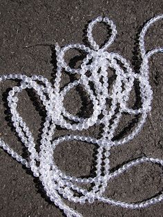 a string sculpture made to look like a flower on the ground, with white beads around it