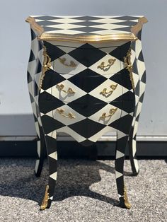 a black and white checkered chest with gold trimmings on the top, in front of a gray wall