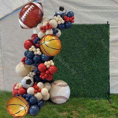 an arrangement of sports balls and balloons in front of a tent