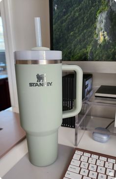 a coffee cup sitting on top of a desk next to a computer keyboard and mouse