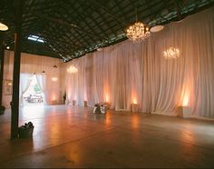 an empty dance floor with chandeliers hanging from the ceiling and white drapes