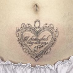 a woman's stomach with a heart shaped tattoo on the side and words written in cursive writing