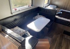 the inside of a motor home with two beds and a table in front of it