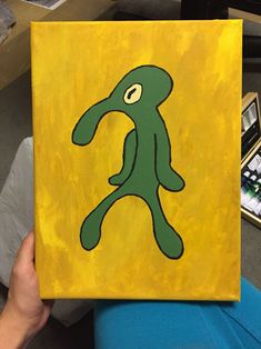 a person holding up a yellow and green painting with an image of a figure on it