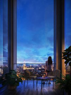 a woman sitting on top of a chair in front of a window looking out at the city