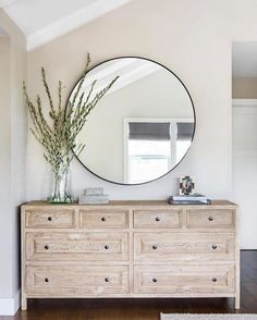 a white dresser with a round mirror above it and an instagram button on the bottom