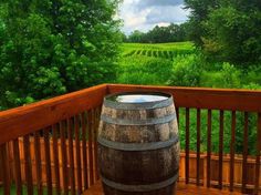 a barrel sitting on top of a wooden deck next to a lush green field and trees