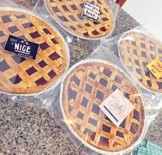 four pies in plastic cases sitting on top of a counter