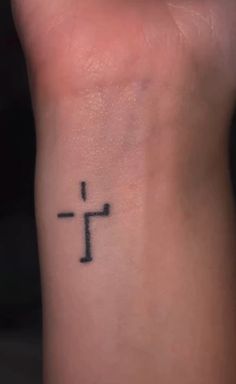 a small cross tattoo on the wrist