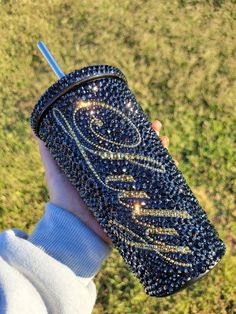 a hand holding a blue case with gold glitters on it and a straw in the other hand