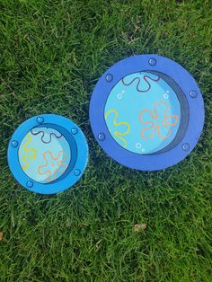 two frisbees laying in the grass with designs on them