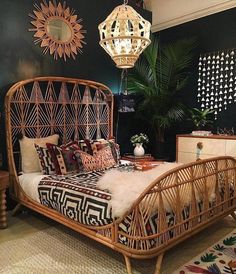 a rattan bed with pillows and blankets on it in a room decorated with plants