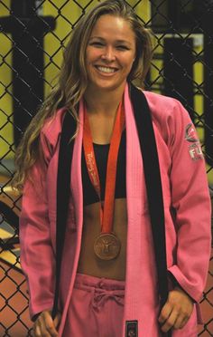 a woman standing in front of a fence wearing a pink jacket and medal around her neck