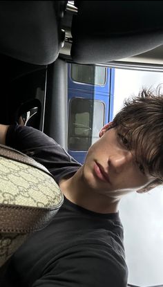 a young man sitting in the back seat of a car next to a snake skin bag