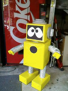 a yellow robot is standing in front of a coke machine