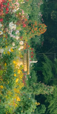 a garden with lots of colorful flowers and trees in the background, along with a yellow fire hydrant surrounded by greenery