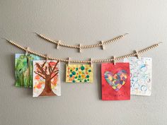 some pictures are hanging from clothes pins on a string and there is a tree in the middle