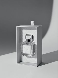 an empty bottle in a white box on a gray background with shadow from the wall