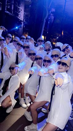 a group of people dressed in white posing for a photo with their hands up and pointing at the camera