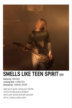 a person with a guitar standing in front of a poster that says smells like teen spirit