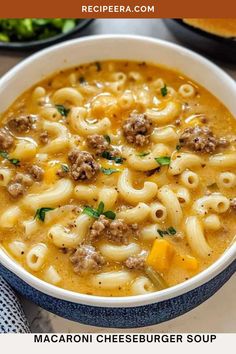 a bowl of macaroni cheeseburger soup on a table with bread in the background