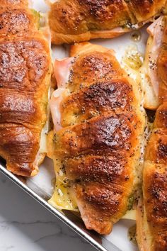 several pieces of bread with ham and cheese on them in a baking pan, ready to be baked