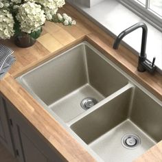 a kitchen sink sitting next to a window with flowers in the vase on the counter