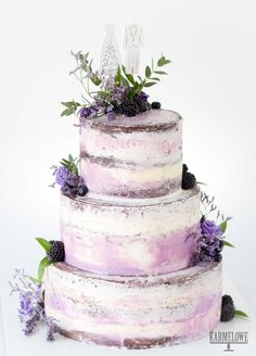 a three tiered cake with purple and white frosting