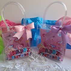 two plastic bags with pink bows and happy birthday tags on them, sitting next to each other