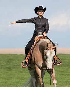 a woman riding on the back of a brown and white horse in a green field