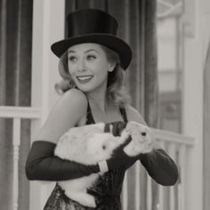 a woman in a top hat holding a cat