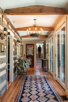 a hallway with a rug and chandelier hanging from the ceiling