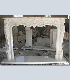 a white marble fireplace surround in a room with rubble on the ground and statues behind it